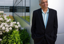 Ramesh Sitaraman standing in front of the Computer Science building and an azalea bush with white flowers