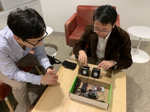 Sunghoon Ivan Lee, left, and Jie Xiong discuss how they will design a smaller device based on the larger prototype apparatus pictured.