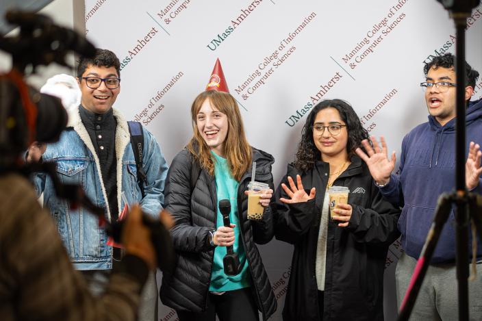 Students recording birthday greetings in front of step- and repeat banner.