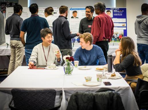 Students chatting at a table during a poster session