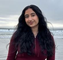 Young woman with long black hair with ocean in background