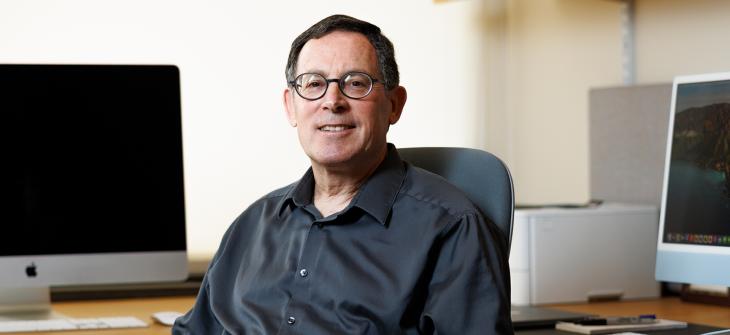 Manning College of Information and Computer Sciences Professor Shlomo Zilberstein sits in front of computers in his office