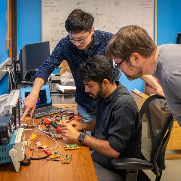 Professor guiding a student on an electronics project